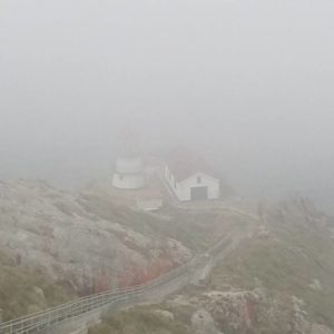 photograph of a lighthouse at the bottom of a long line of stairs, mostly shrouded in fog