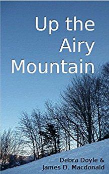 book cover for Up the Airy Mountain by Debra Doyle and James Macdonald, is a snowy woods scene with the title in white lettering on the blue sky and the authors' names in black lettering on the snow